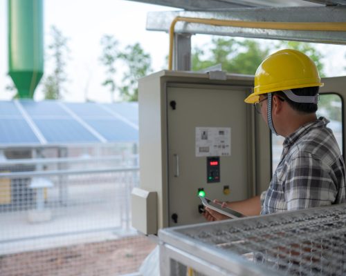 Technician at groundwater pumping station with solar or alternat Technician at groundwater pumping station with solar or alternative energy uses a tablet to control and monitor.